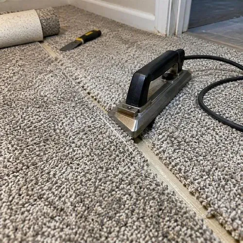 Carpet seam being joined with a hot-melt seaming iron