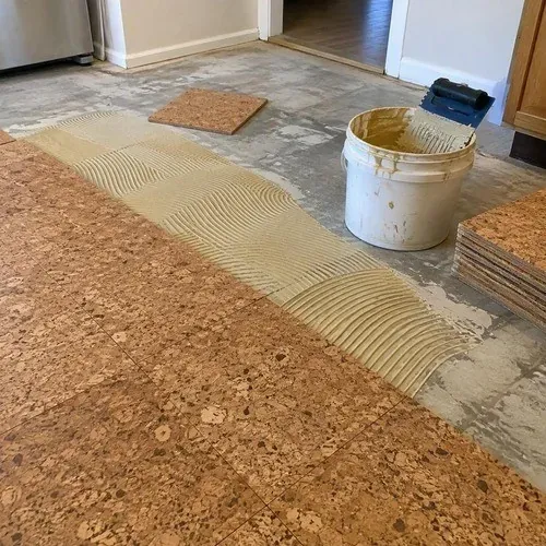 Cork floor tiles being laid into contact adhesive with a trowel