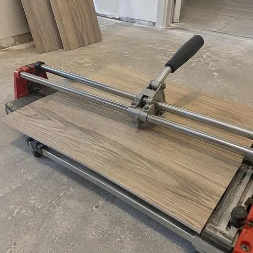Porcelain tile being scored on a manual rail cutter