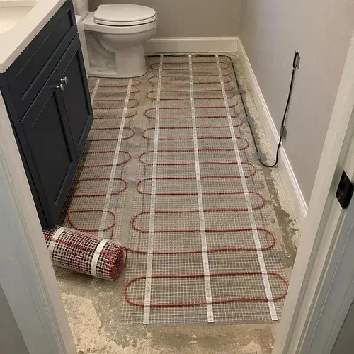 Electric radiant floor heating mat rolled out with its floor sensor wire