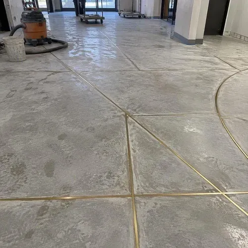 Brass terrazzo divider strips laid out on a prepared concrete slab