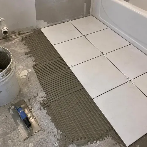 Thinset mortar combed with a notched trowel as the first floor tiles are set